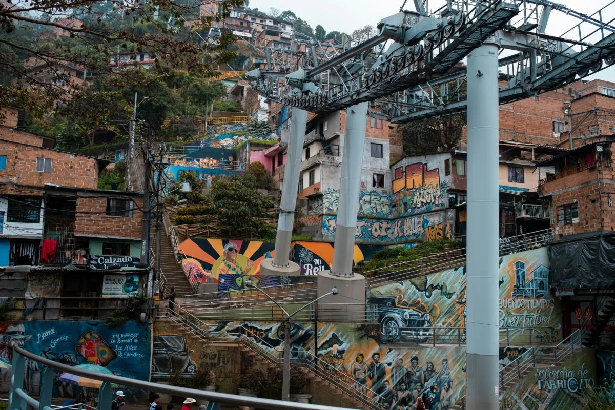Comuna 13 with houses stacked on the side of a hill, colorful street art and power lines.