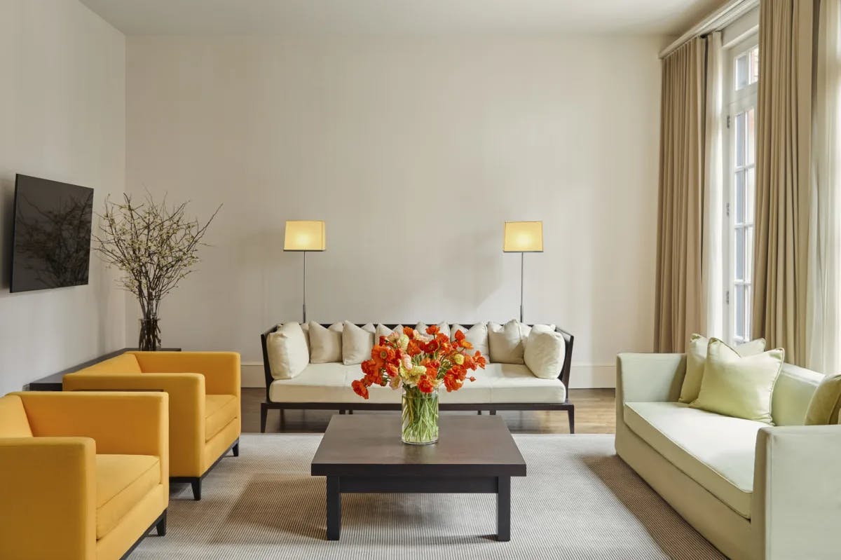 a chicly minimalist living room with orange chairs, a green couch, and a bouquet of flowers on a coffee table