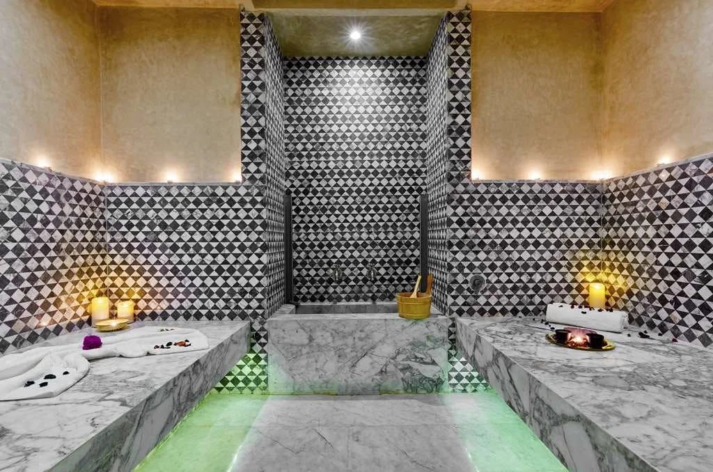 Checkerboard-like Moroccan tiles fill stone walls while marble slabs provide seating in a spa at Hyatt Regency Casablanca