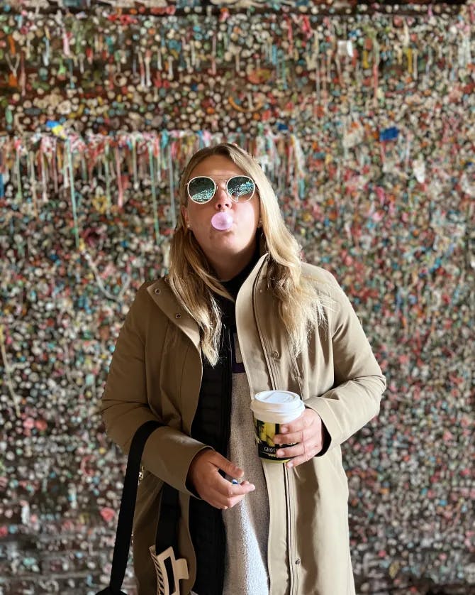 bubble gum wall with Brittany blowing a bubble with a coffee in hand. 