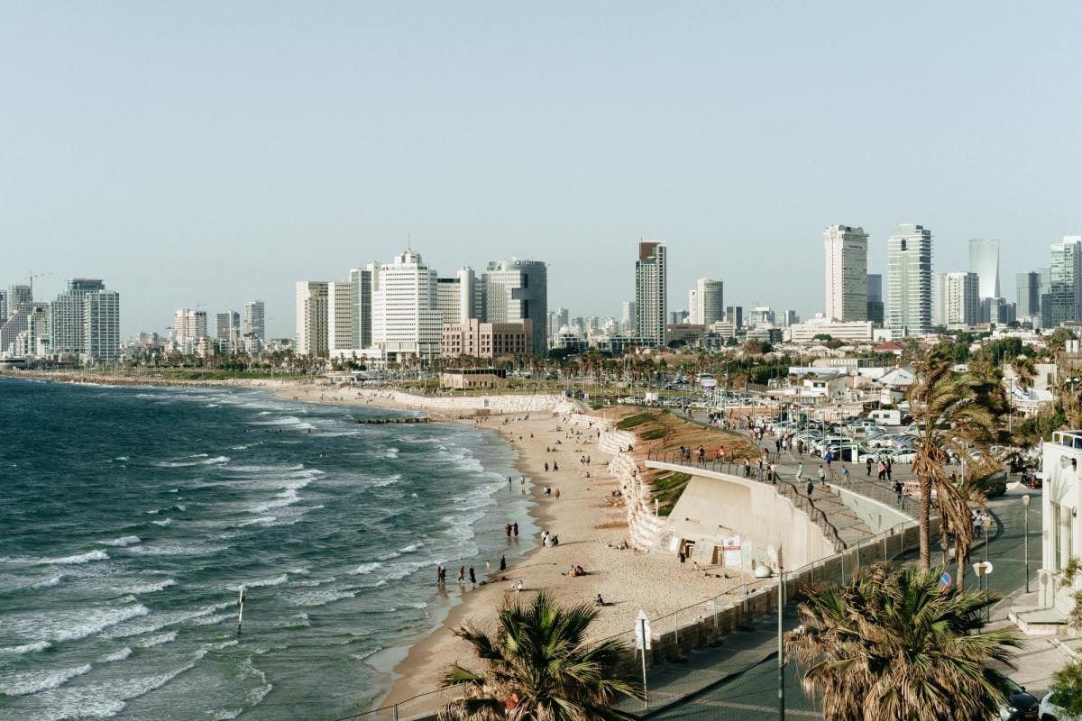 People enjoying the beach on a clear day next to bustling city of Tel Aviv.