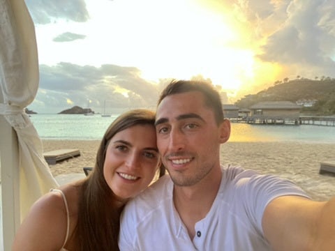 Travel Advisor Kali Hietpas with her boyfriend in front of a beach at sunset.