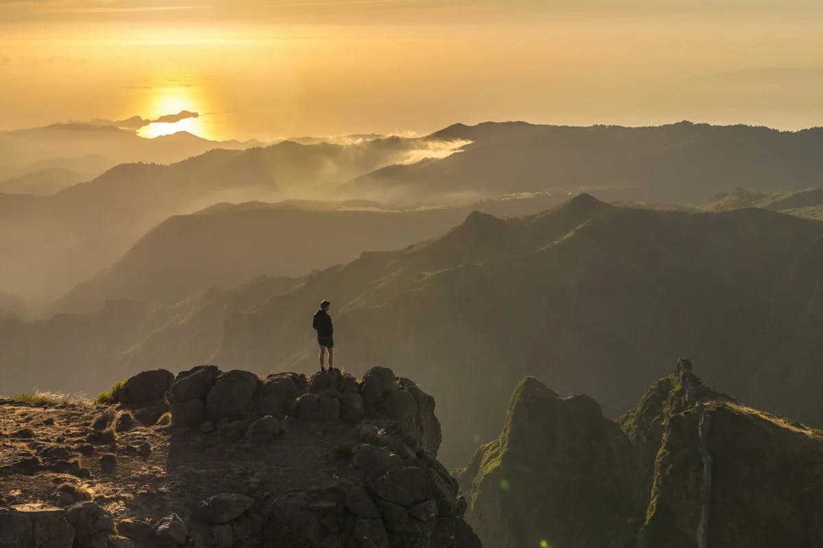 A person hiking a mountain during a sunrise