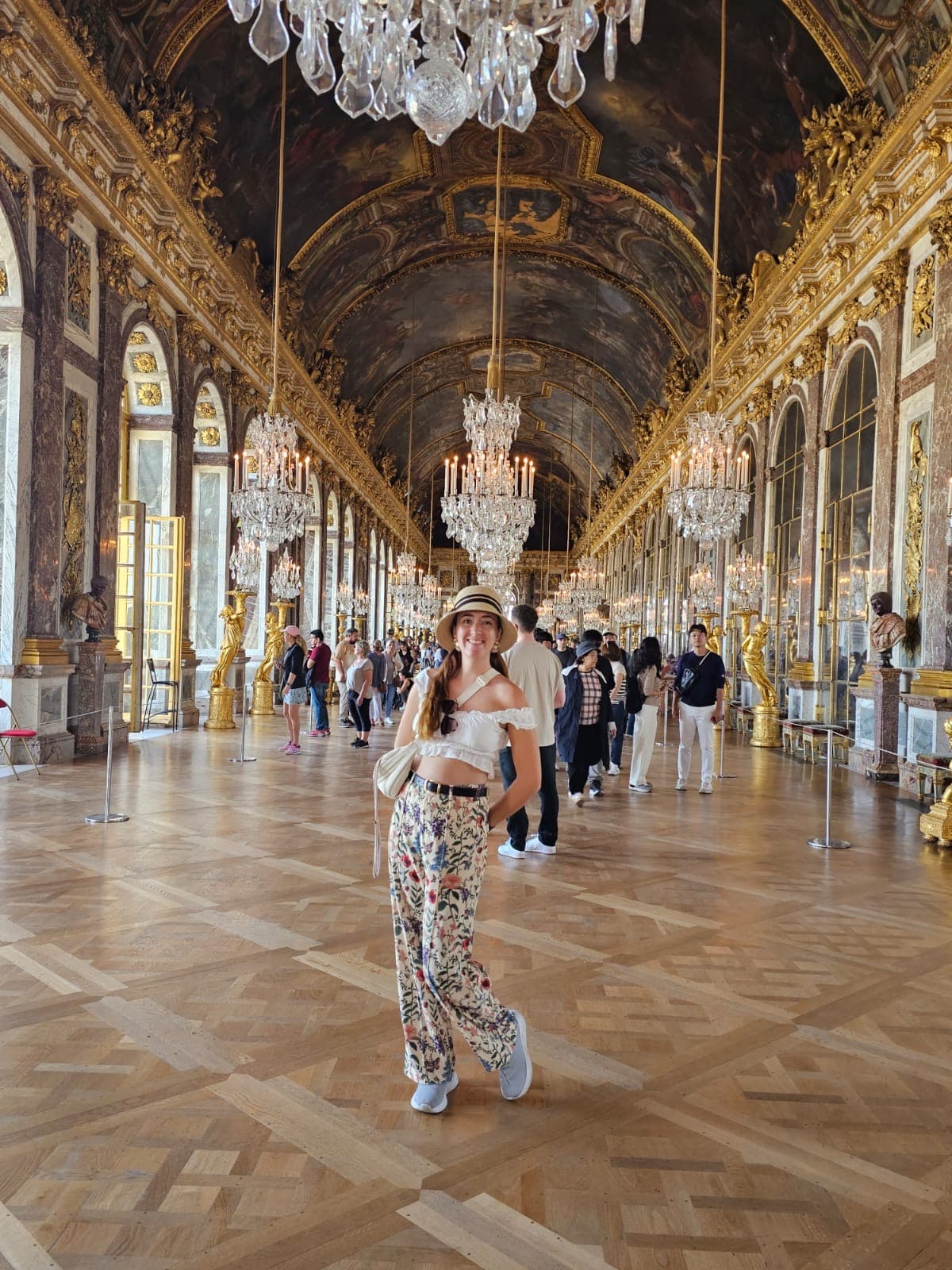 Picture of Alexandria at Palace of Versailles in front of chandeliers in a grand hallway