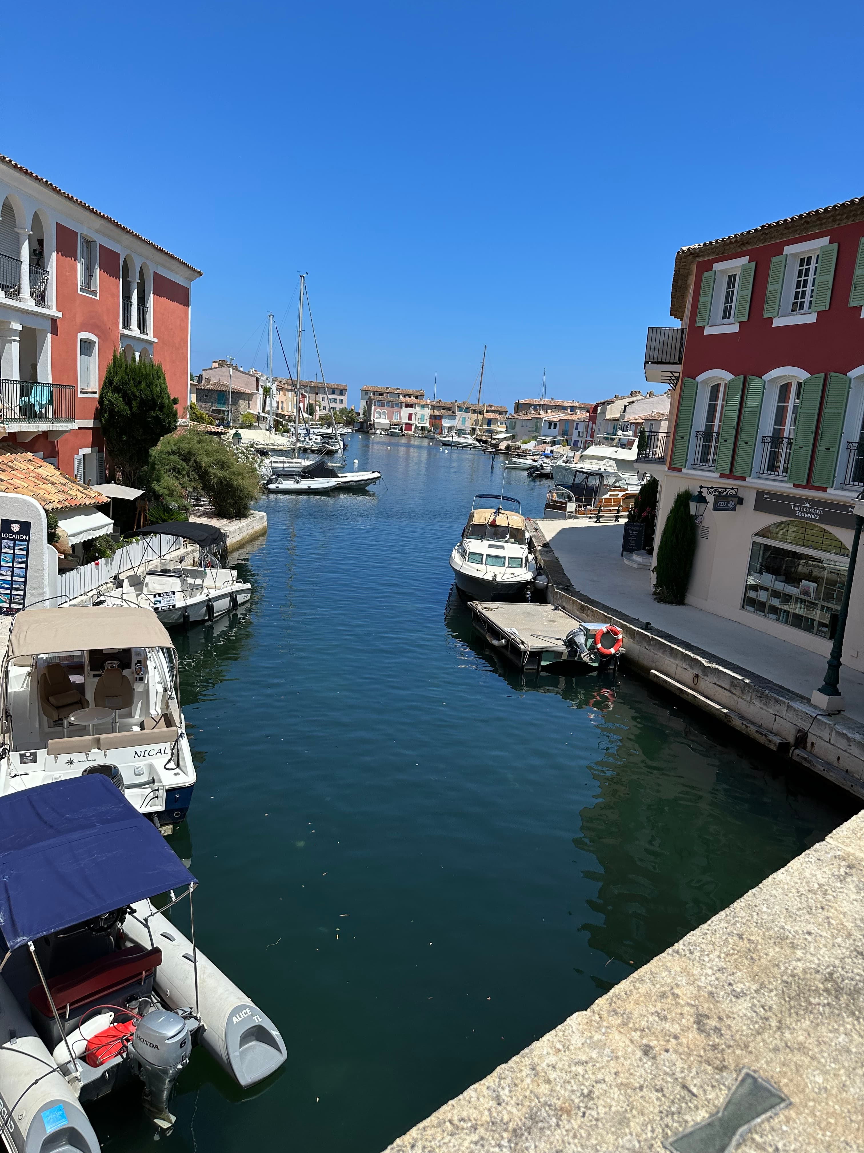 Picture of Port Grimaud featuring a water canal and two red-toned buildings on each side surrounded by docked boats