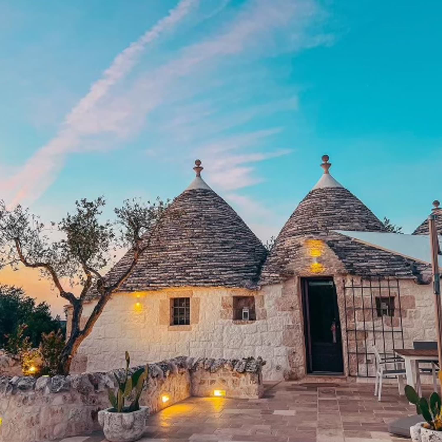 Picture of beautiful Trullo Perla Greta house with an illuminated path in front of it at dusk