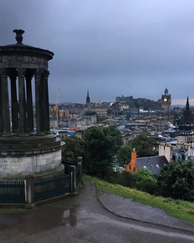 A picture of Calton Hill overlooking a city at dusk