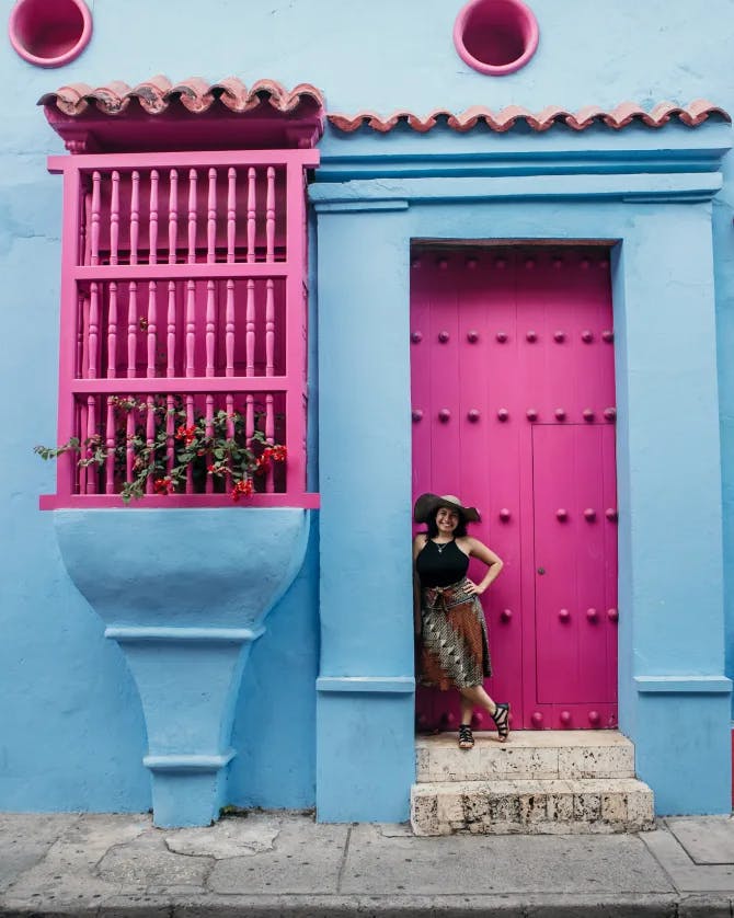 Travel Advisor Diana Morales standing in front of a pink and blue building.