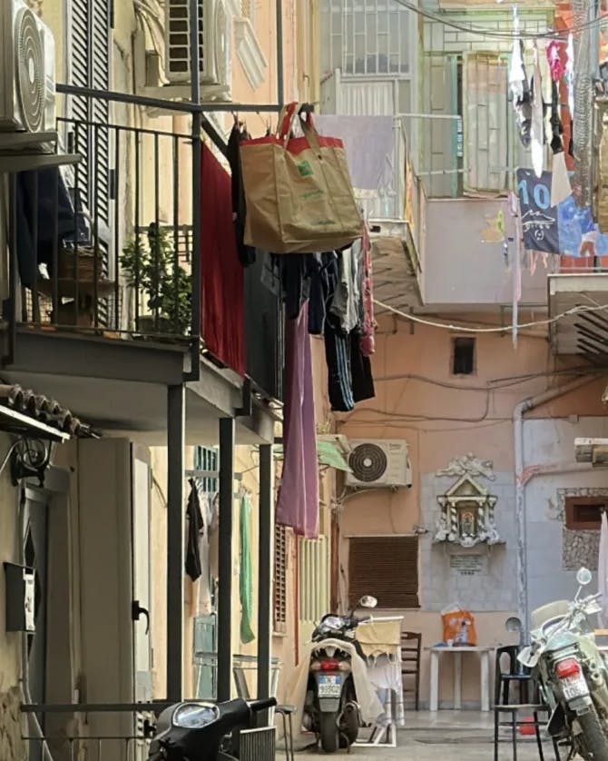 A photo of the street with a lot o clothes hanging on the balcony