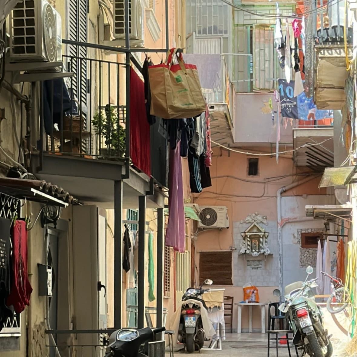 A photo of the street with a lot o clothes hanging on the balcony