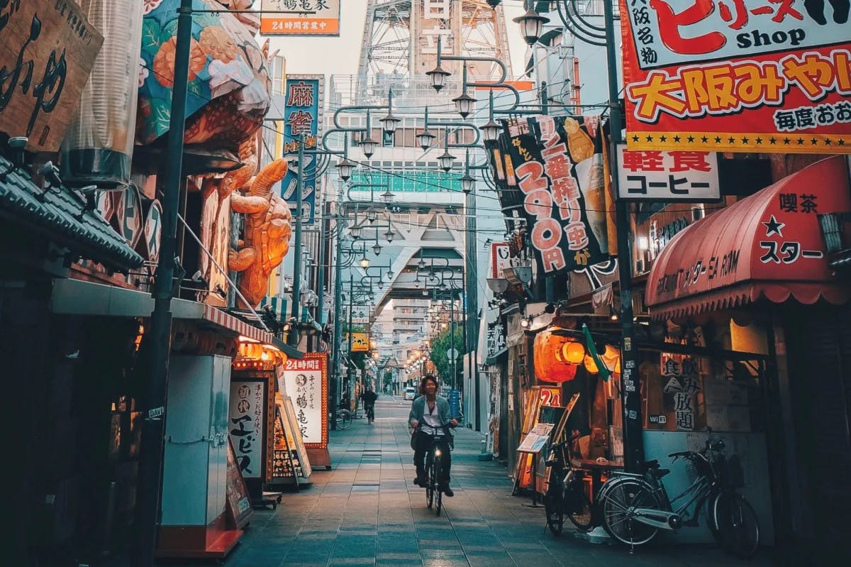 man riding a motorcycle through a colorful Japanese alleyway