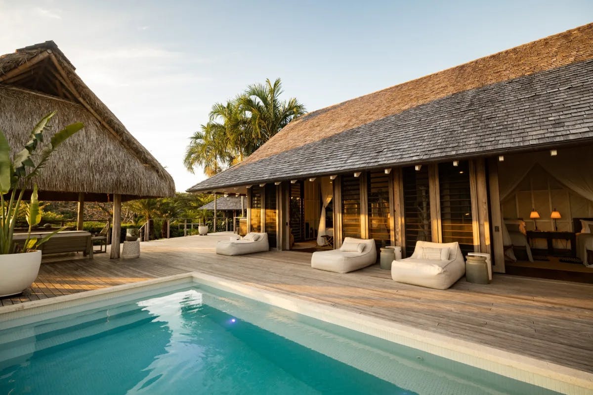 a pool on a wooden deck of a thatched-roof casita