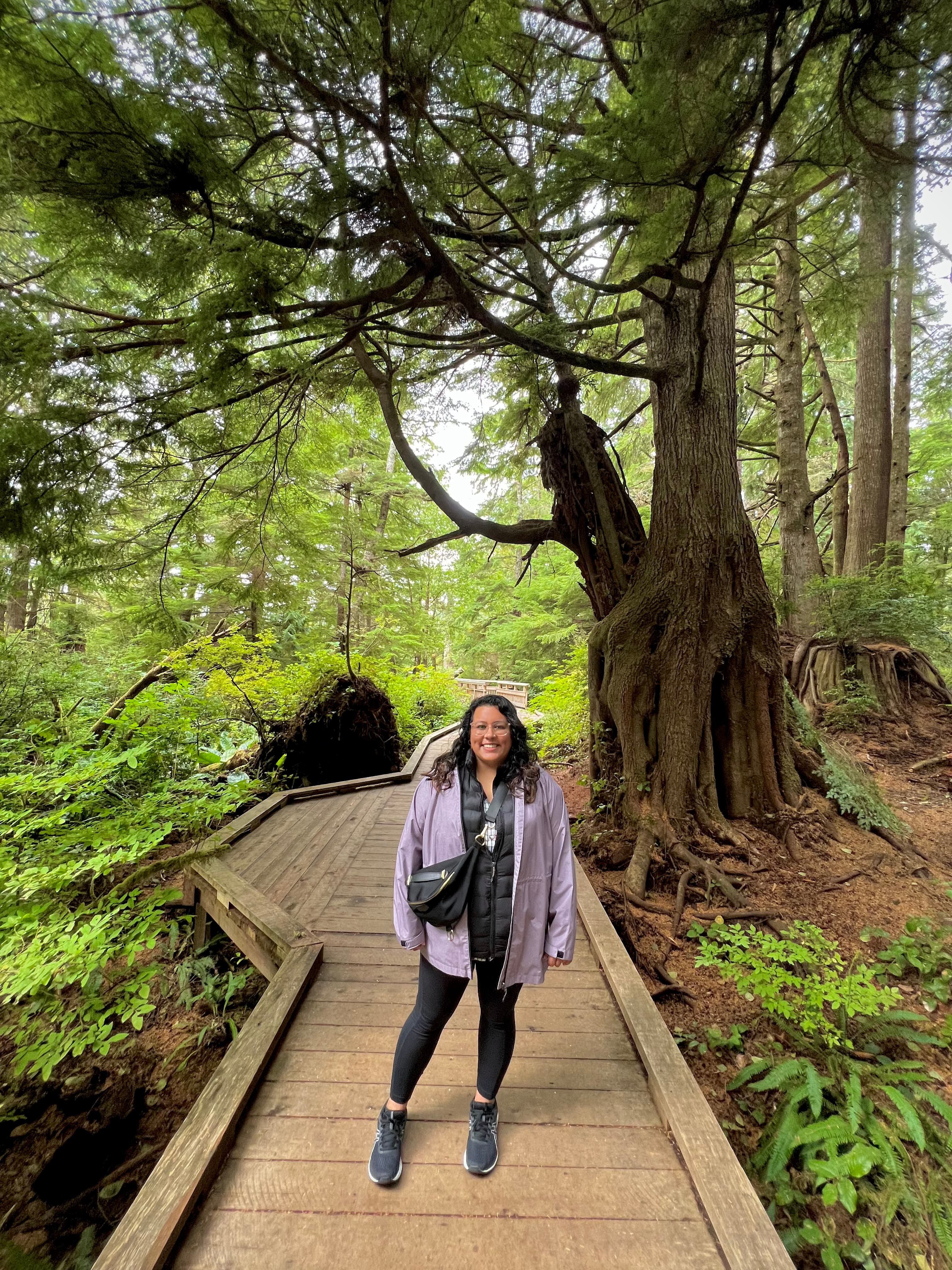 Pooja smiling on a wooden foot bridge amidst a wooded wonderland.