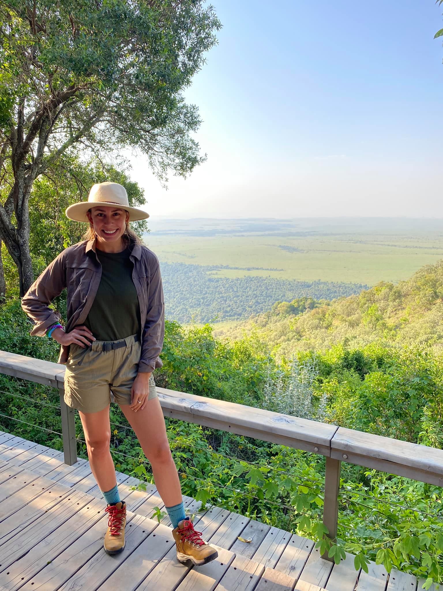 Travel advisor posing in front of an overlook of a lush green jungle.