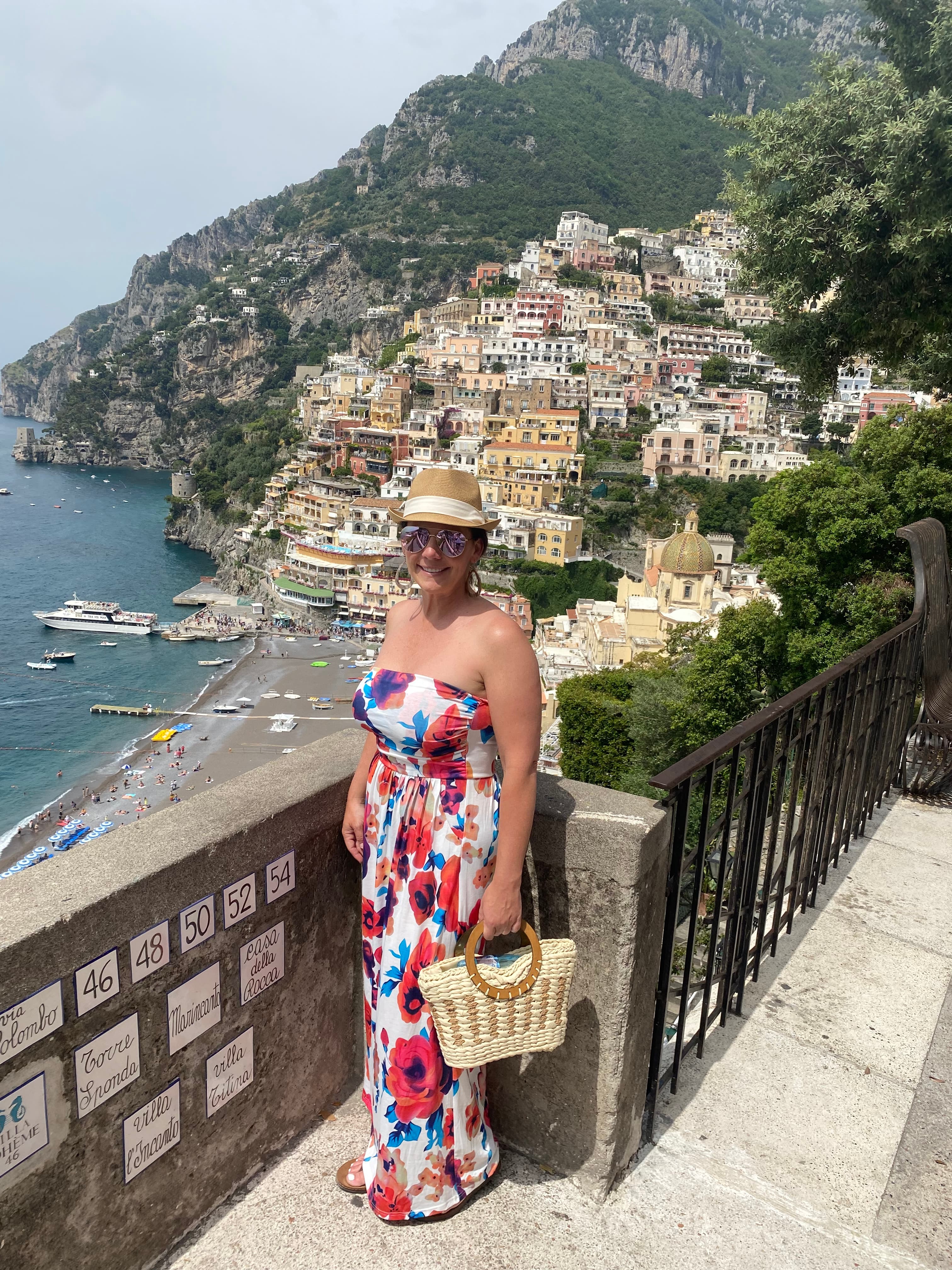 Woman posing on an overlook of a cliff-side coastal town