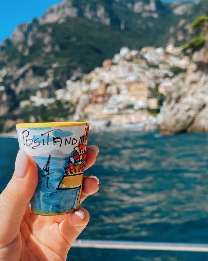 Holding a travel souvenir over the sea and Italian coast