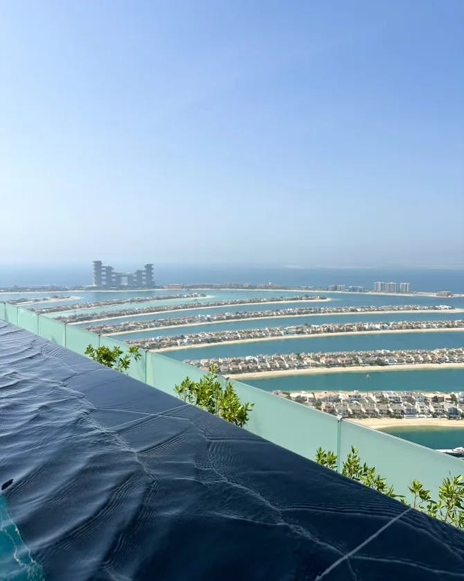 An aerial view of AURA SKYPOOL Dubai with buildings and water in the background