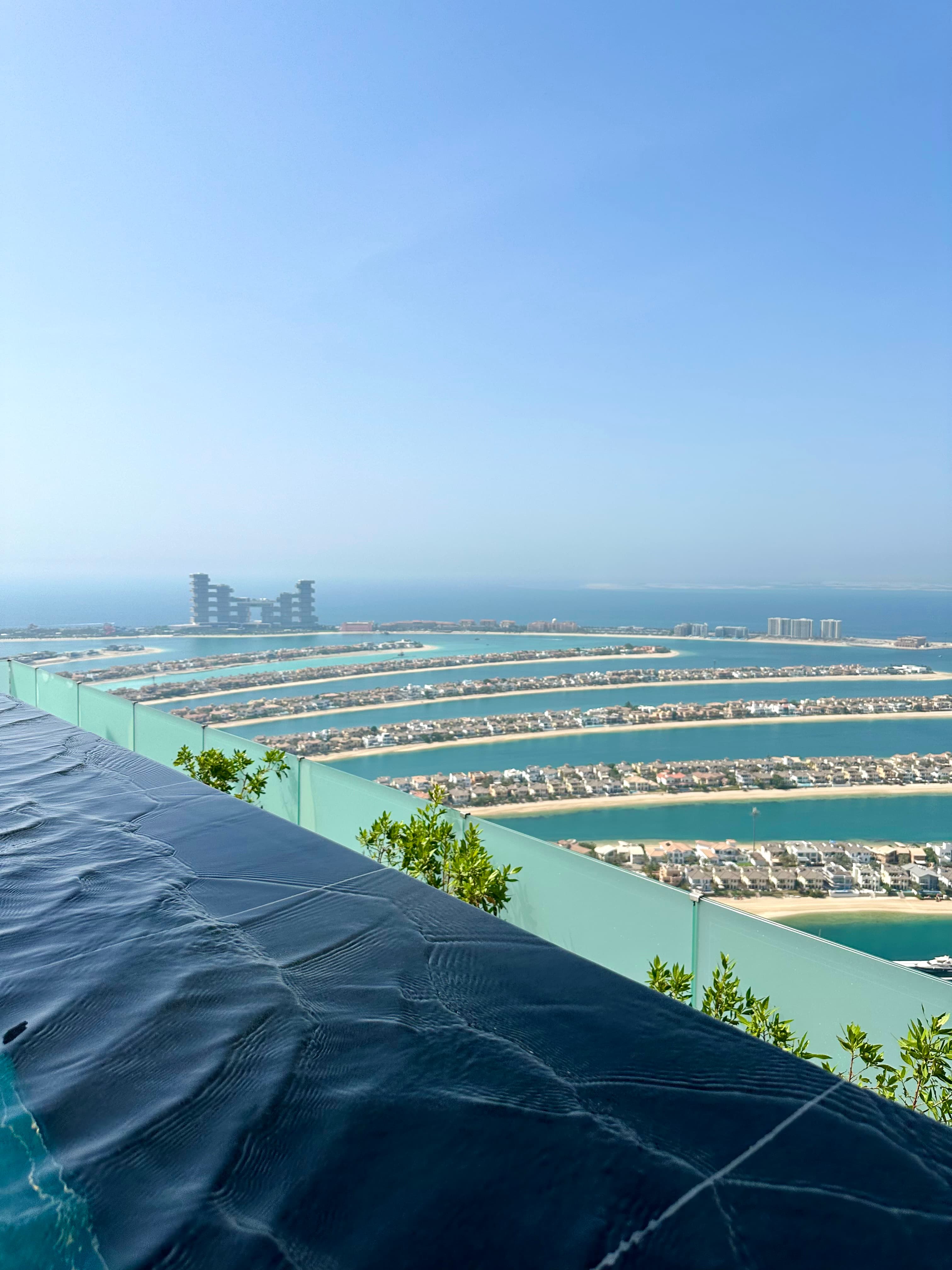 An aerial view of AURA SKYPOOL Dubai with buildings and water in the background