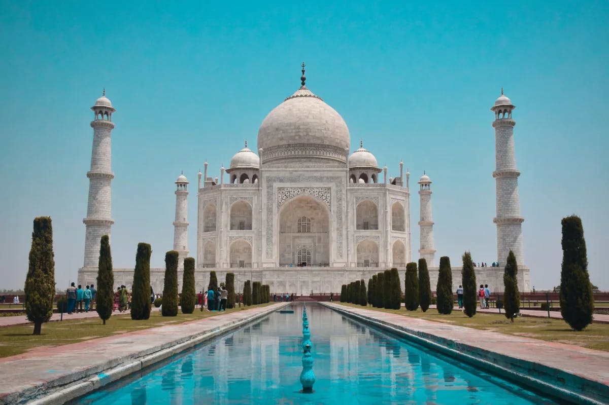 Turquoise waters of the fountains in front of the Taj Mahal mirror blue skies as visitors marvel at the historic wonder