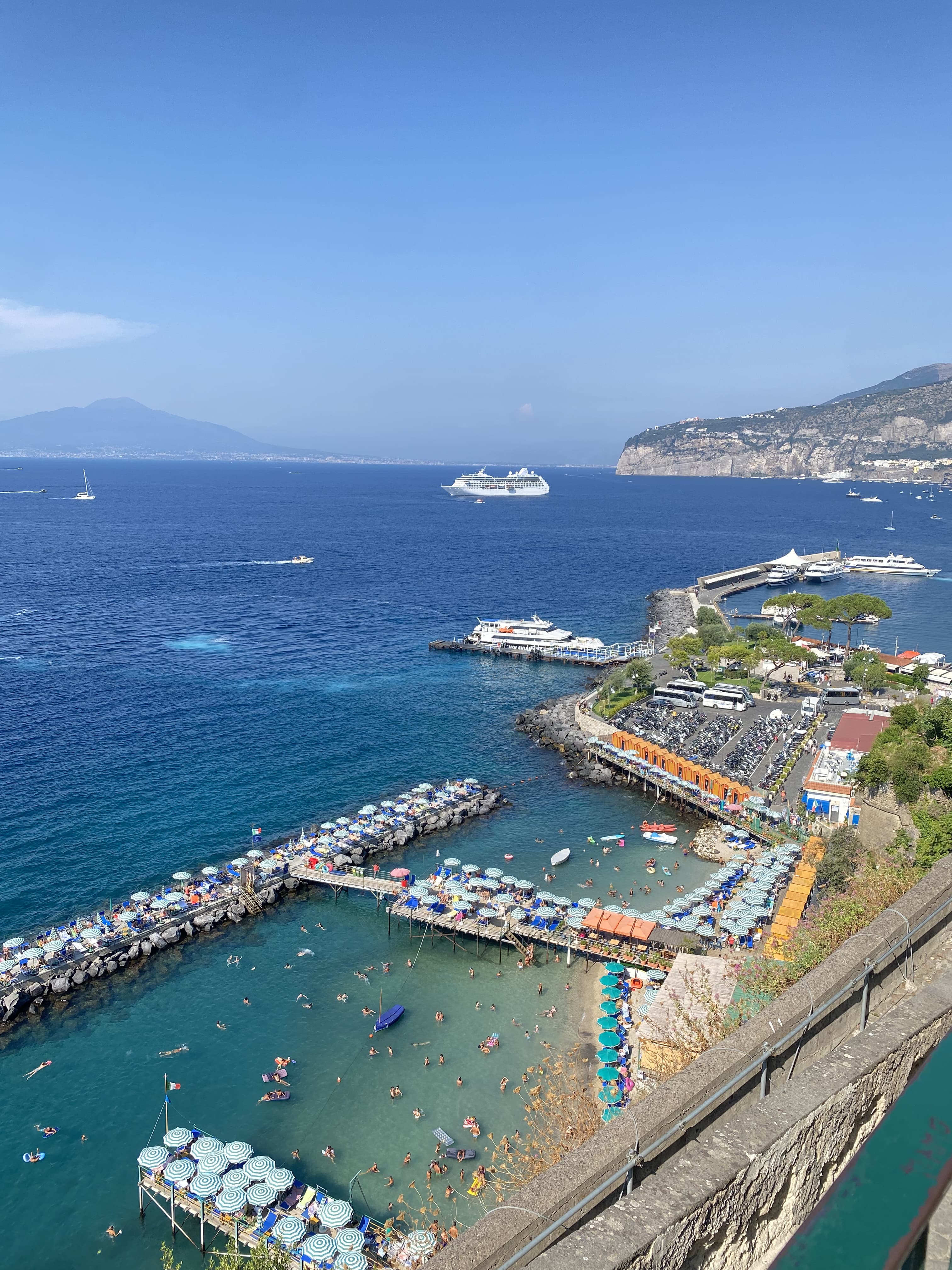 Photo from high up with a descending view of a sea side town with boat docks and clear skies.