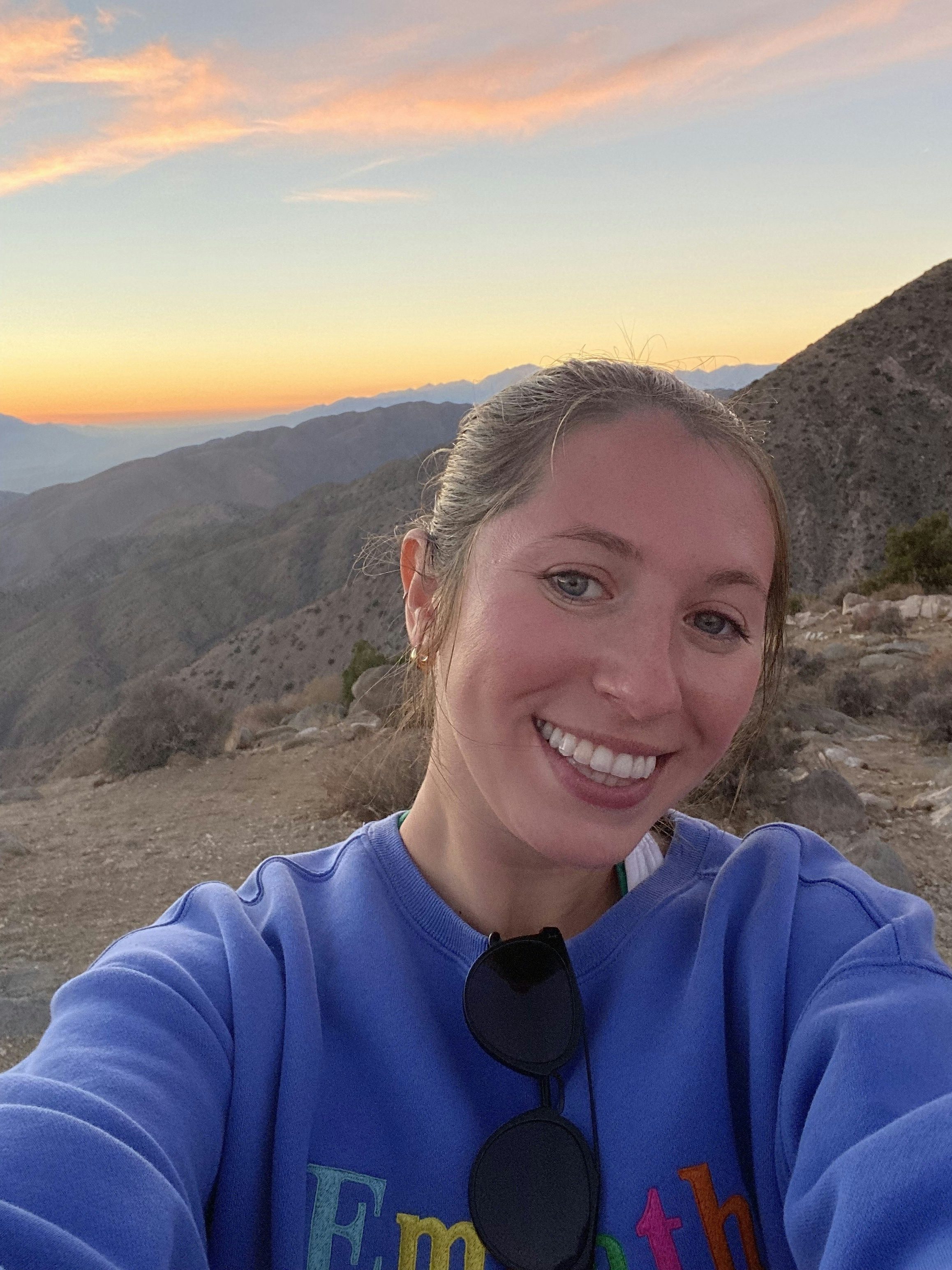 Travel Advisor Meryl Honig with a blue sweatshirt at sunset in the mountains.