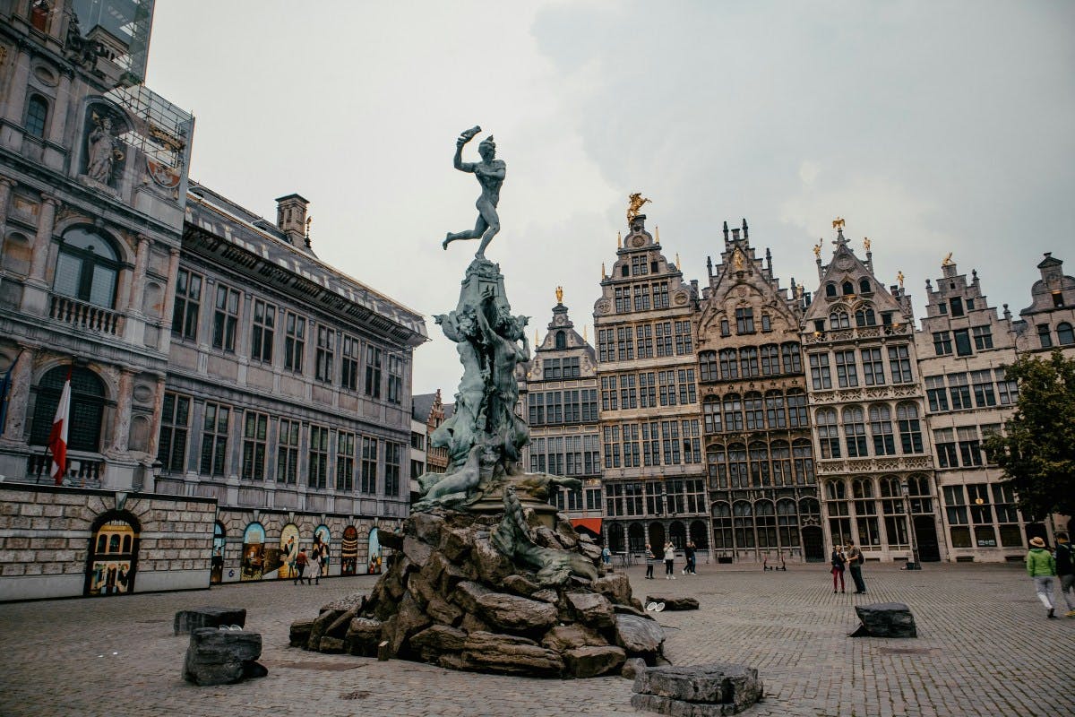 A large statue in the middle of a town square surrounded by tall buildings.