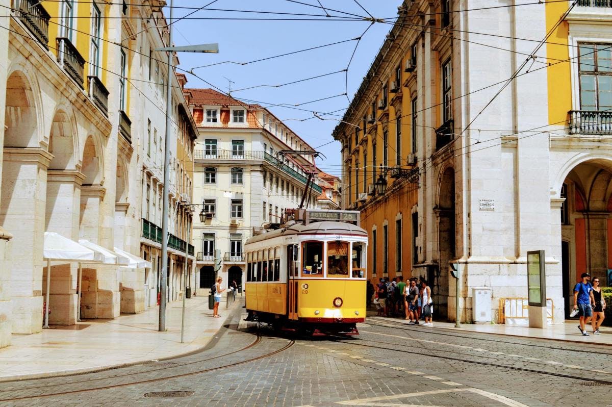 Yellow cable driving through downtown Lisbon on a sunny day.