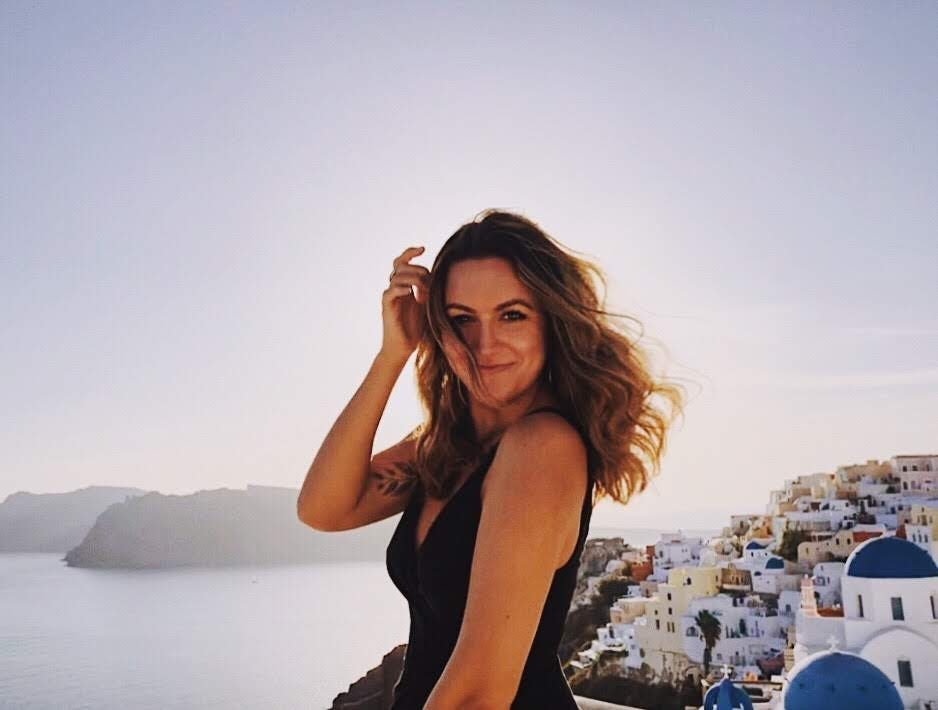 Travel Advisor Breanna Rogers in Greece with blue and white colorful building in the distance.
