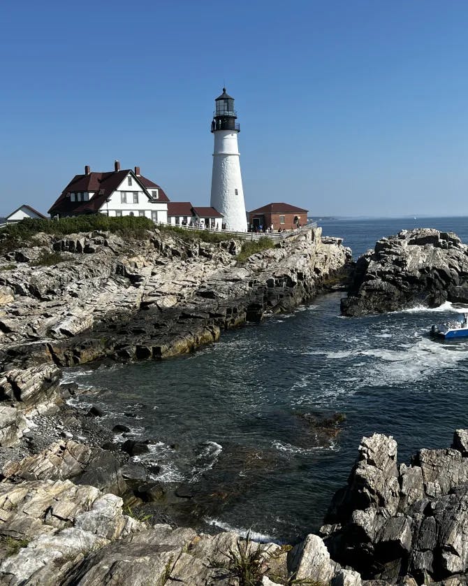 Picture of a lighthouse in Portland overlooking blue water and a rocky shoreline