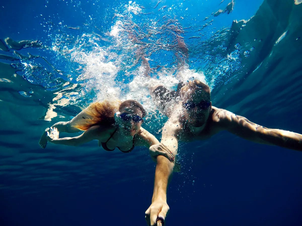 A picture of a cheerful couple diving into the water.