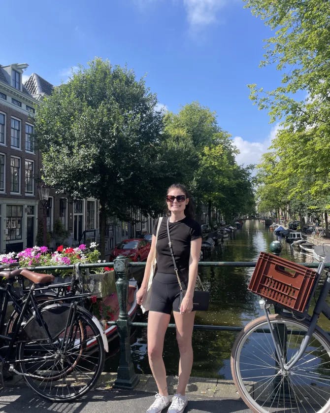 Picture of Bridget wearing a black outfit standing next to bicycles in Amsterdam