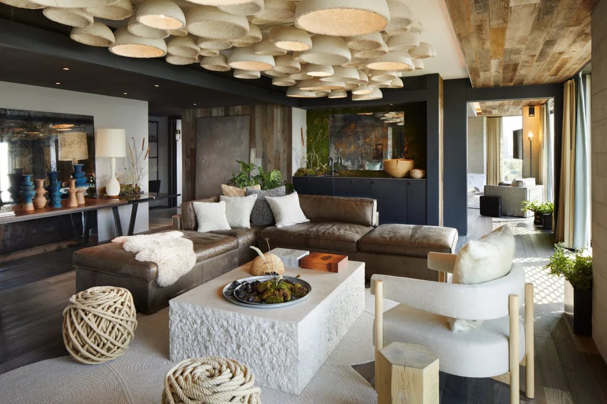a chic living room with a gray L-shaped couch, white chairs and a ceiling covered with white conical art structures