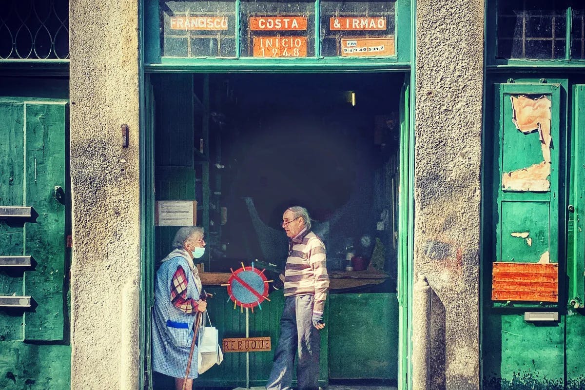 The image captures a scene outside a shop with two people standing at the entrance. 