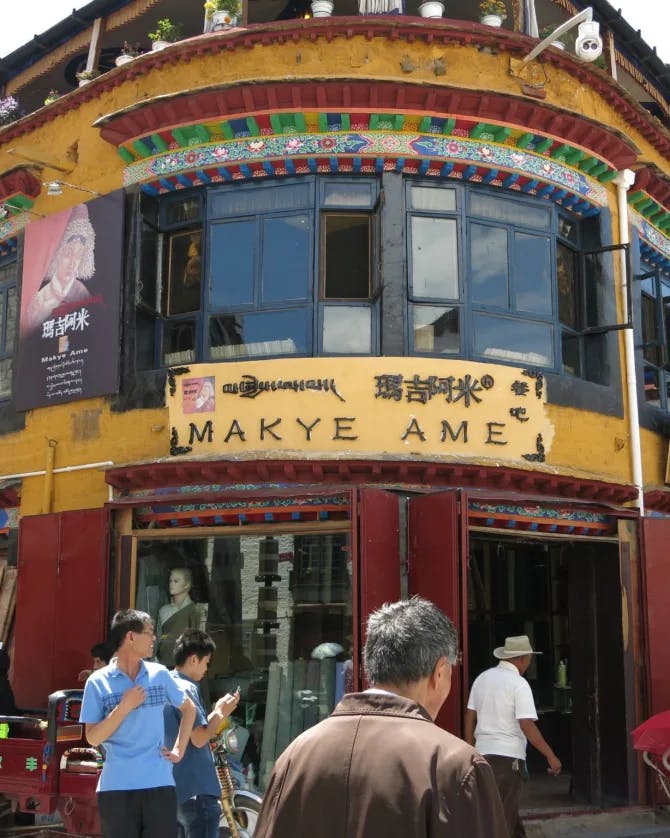 A red and gold building exterior with signage and people walking outside around it. 