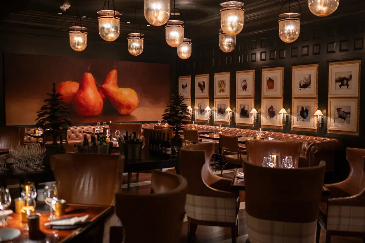 a dimly lit restaurant with a painting of pears hanging on the wall