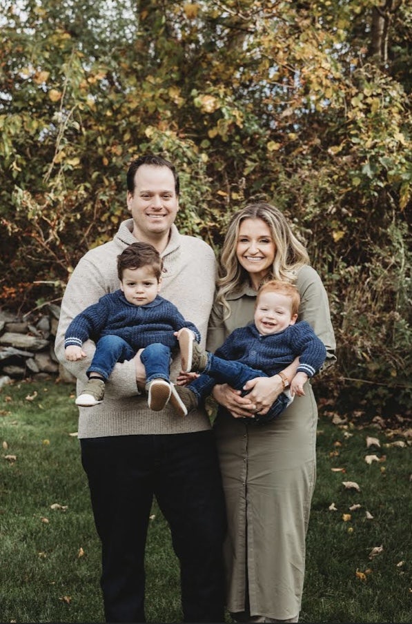 Melissa Schwartz smiling with her husband, each holding two young boys in their arms