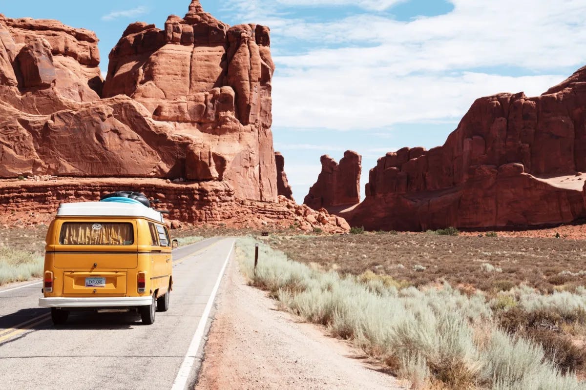 A camper van driving along a barren highway somewhere in the Arizona desert