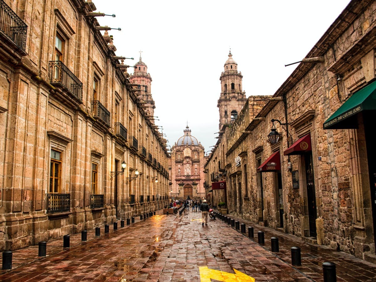 Cobblestone street between beige stone buildings in Mexico City.
