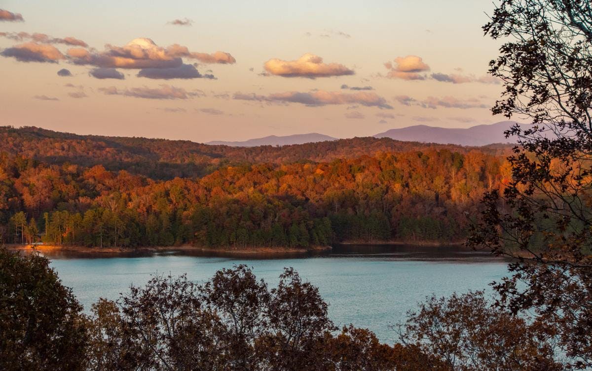 Carters Lake in Georgia surrounded by fall trees and mountains during sunset. 