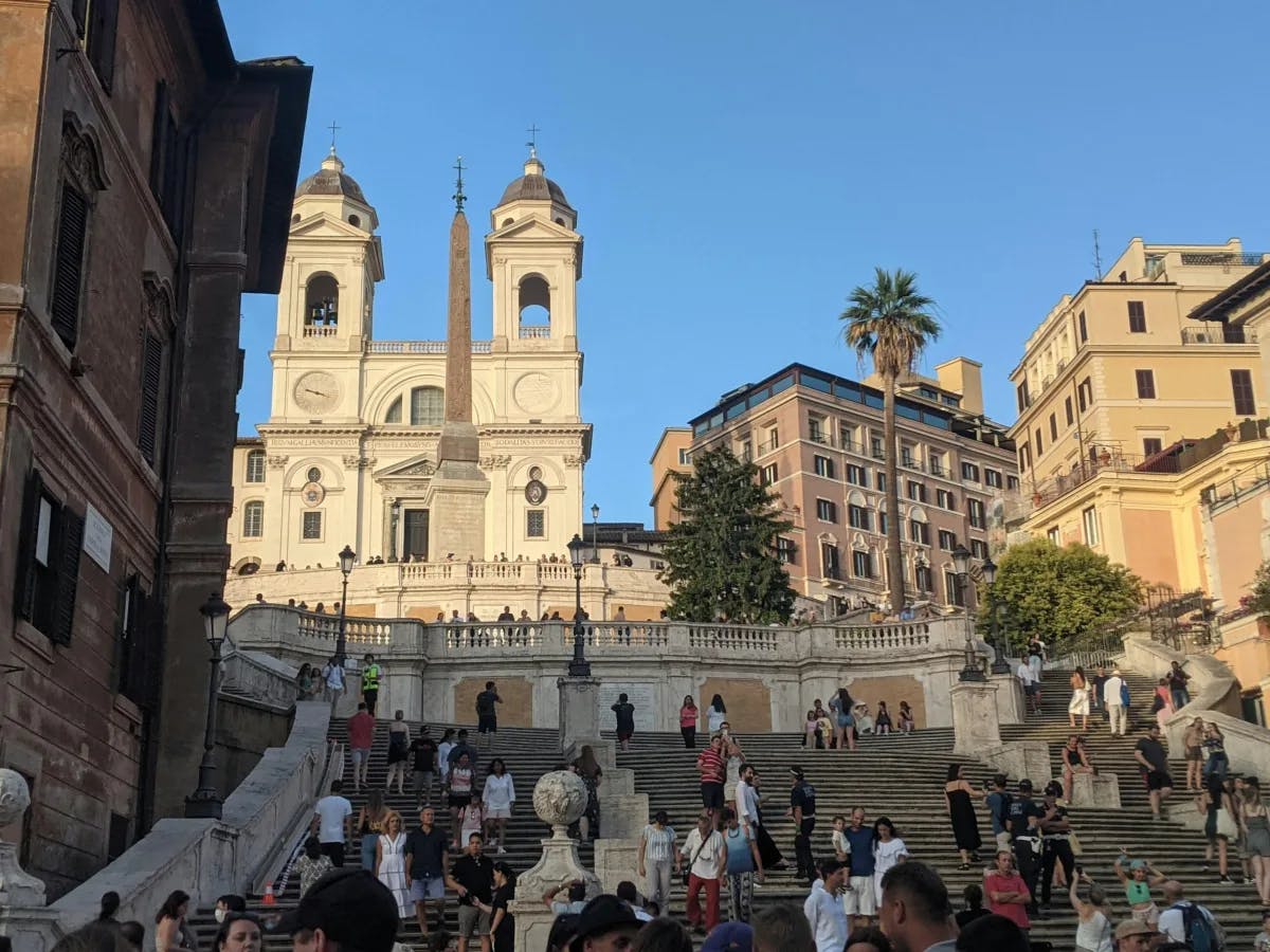 A picture of a group of people walking up and down the Spanish Steps during the daytime.