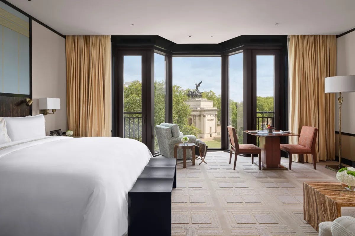  a grand hotel room with floor-to-ceiling windows overlooking a leafy park