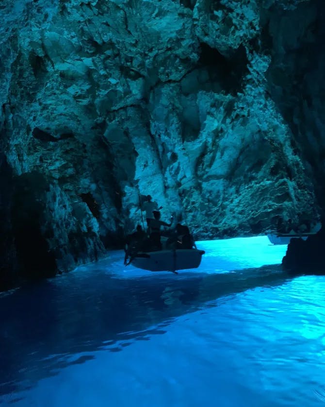 A picture of a rocky cave with glowing blue water