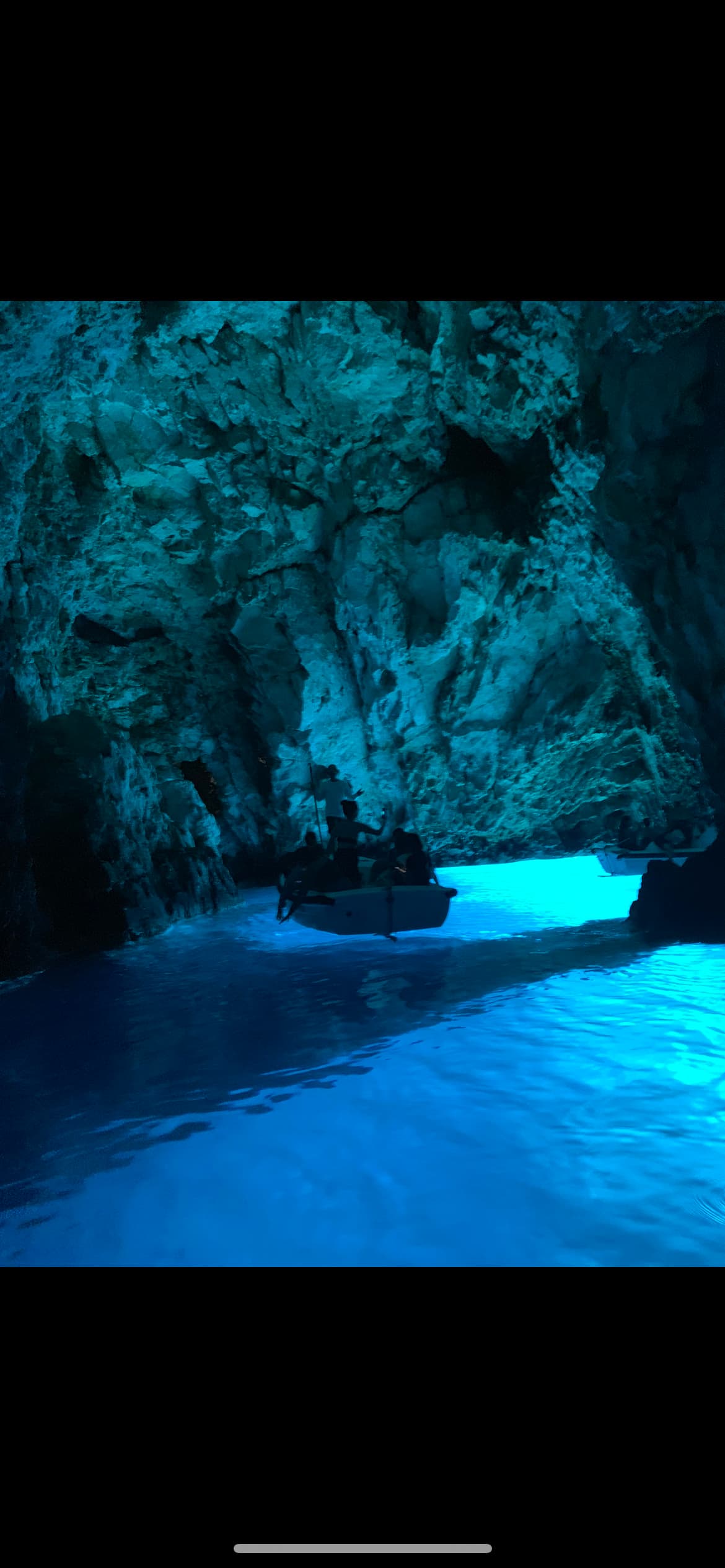 A picture of a rocky cave with glowing blue water