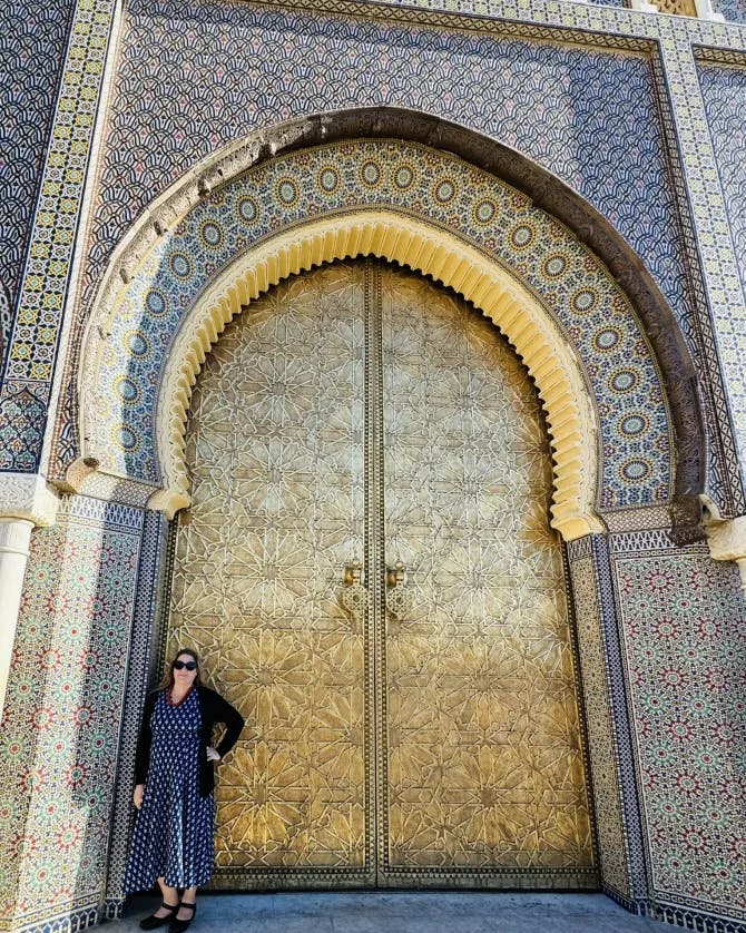 Karyn standing in front of the Royal Palace with golden doors and beautiful arch way. 