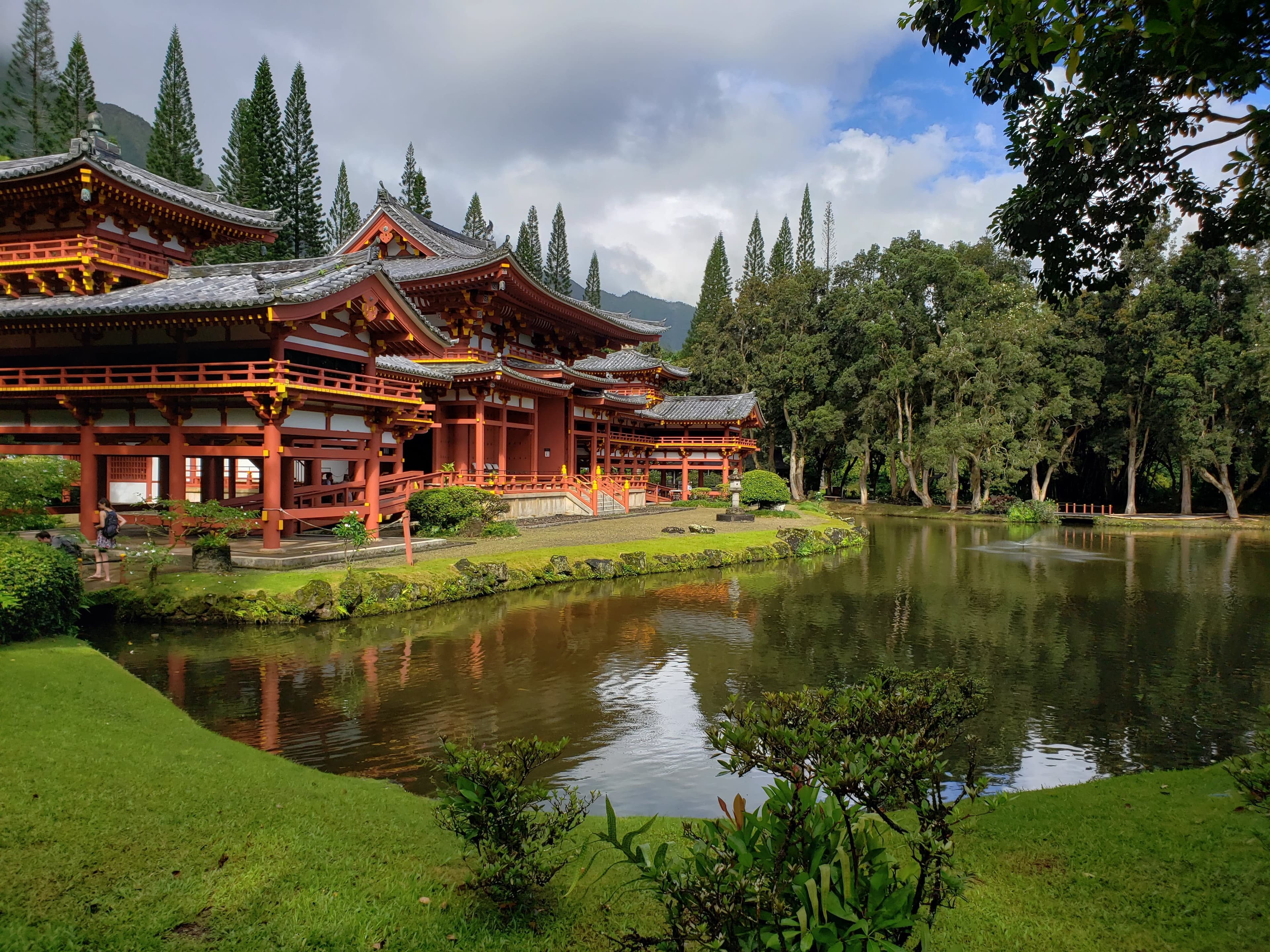 Byodo-In Temple surrounded by lush, green grass and trees, and a small lake.