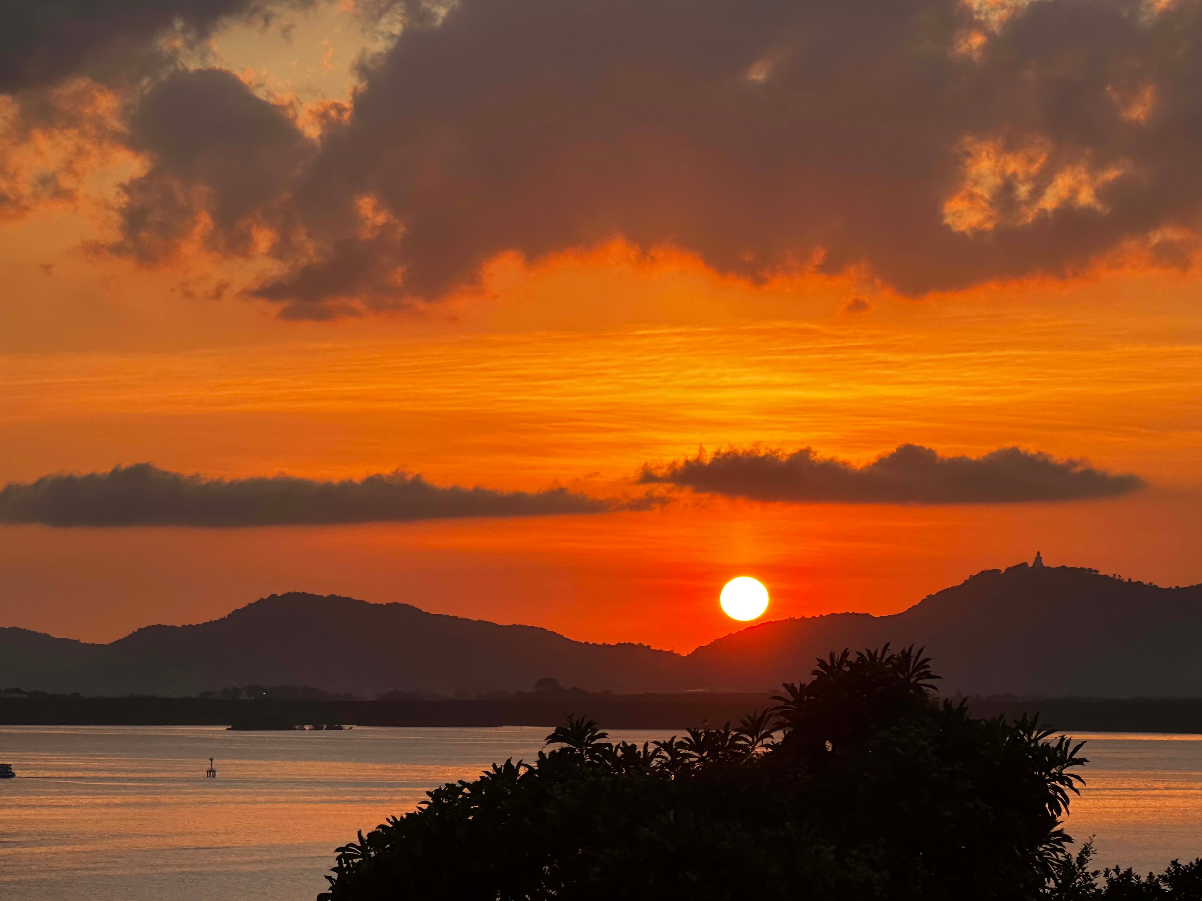 Beautiful view of sunset with different shades of orange, over the ocean and mountains