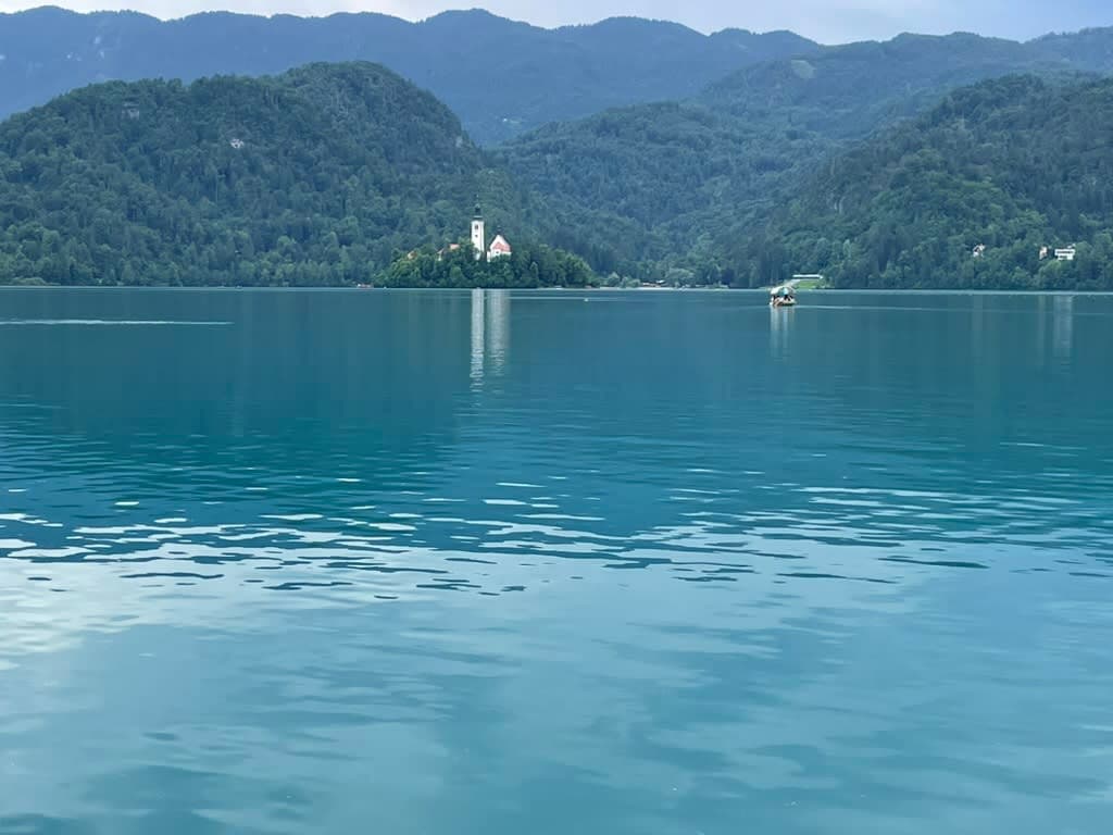 Lake Bled and the shoreline with a house on a green island in the distance