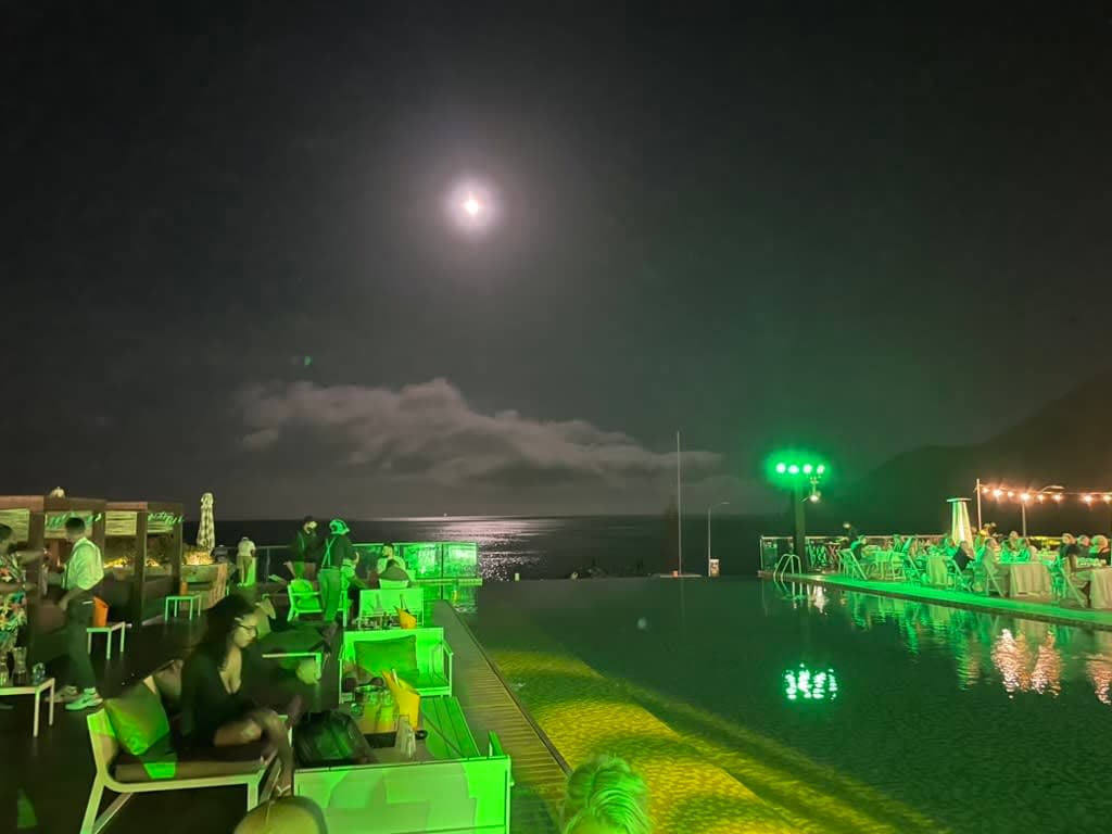 A green-lit pool and pool deck at night