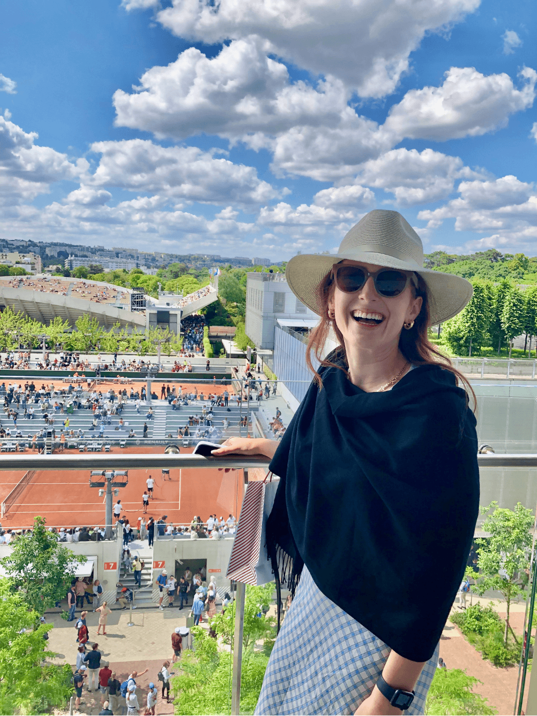 Fora Advisor Hannah in a blue sweater, skirt and straw hat on a balcony overlooking a hillside