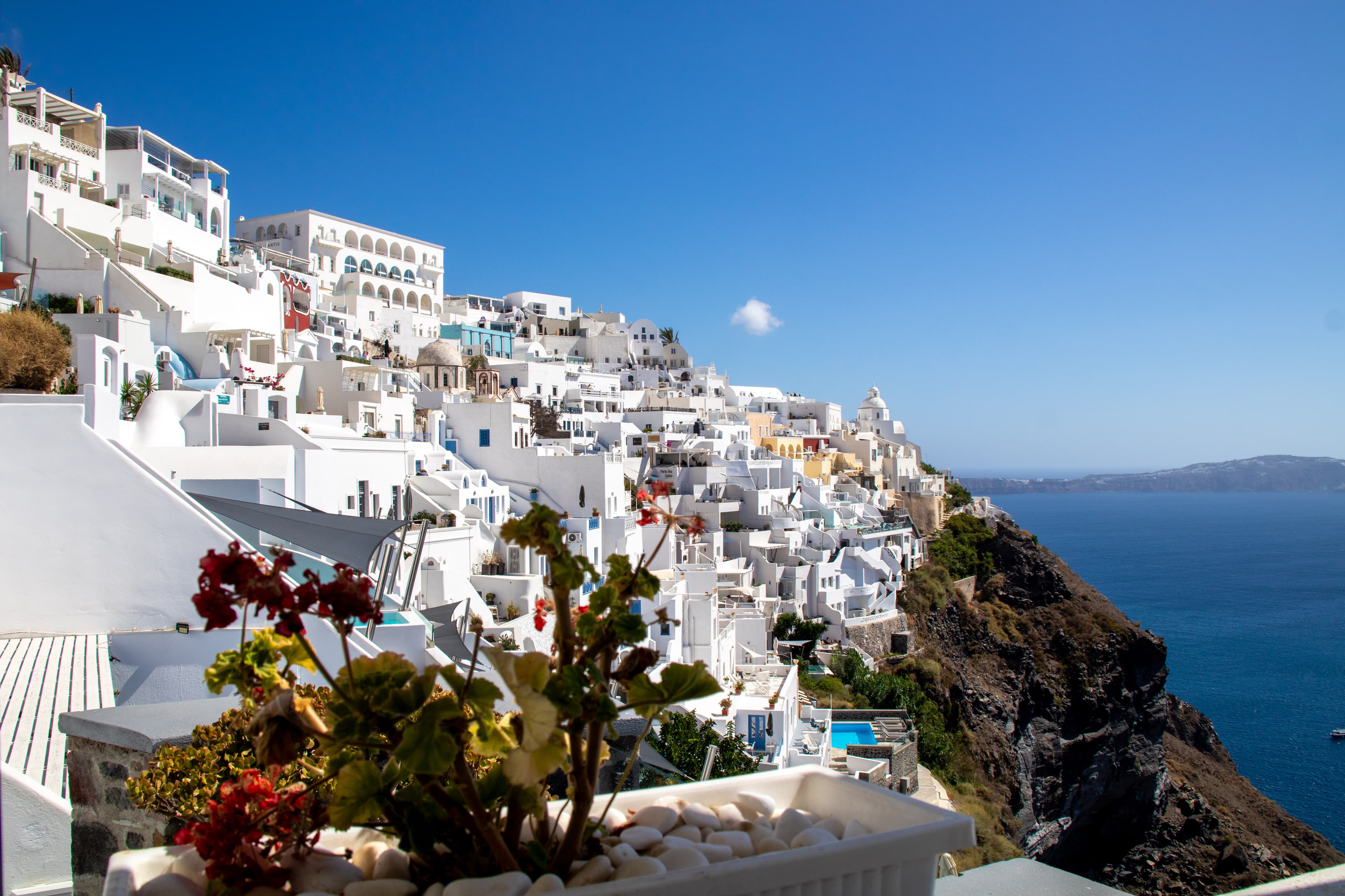 A cliffside in Santorini with white buildings and the ocean in the background